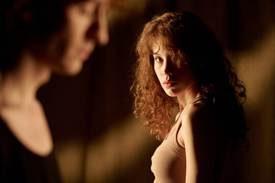 Medium close up of attractive young woman looking at her unrecognizable boyfriend sadly