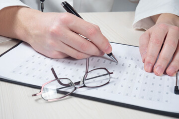 A health worker records information about a patient's health condition in a medical record. Close-up.