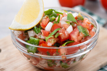 Traditional Mexican Pico de Gallo sauce in bowl on wooden table