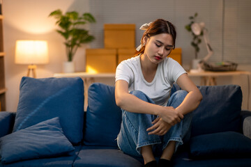 A woman is sitting on a blue couch with her hands on her knees