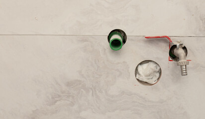Close-up view of plumbing installation with exposed pipes and a faucet handle on a tiled wall. A...
