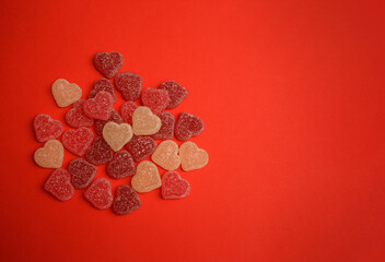 Heart-shaped gummy candies on a vibrant red background, symbolizing love and romance. Perfect for Valentine's Day themes, holiday promotions, greeting cards, and romantic celebrations