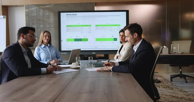 Two parties represented by business professionals reviewing, signing contract at conference table during negotiation, shake hands as gesture of mutual respect, finalize successful completion of deal