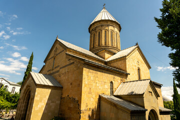 A large, brown building with a steeple and a cross on top. The building is surrounded by trees and has a peaceful, serene atmosphere