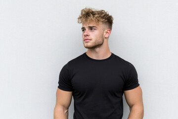Obraz premium A man with a shaved head and a beard stands in front of a white wall