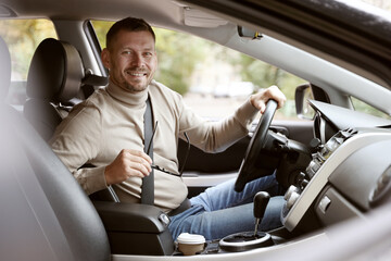 Happy man behind steering wheel of modern car