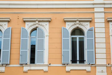 Arched windows with white wooden shutters in yellow wall