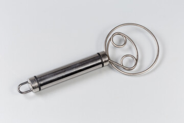 Stainless steel hand kitchen whisk on a gray background
