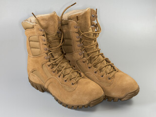 Pair of insulated beige leather combat boots on gray background