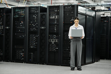A skilled woman in a white shirt engages with server hardware in a high-tech environment.