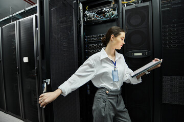 A woman in a white shirt works intently in a modern server room setting up network configurations.