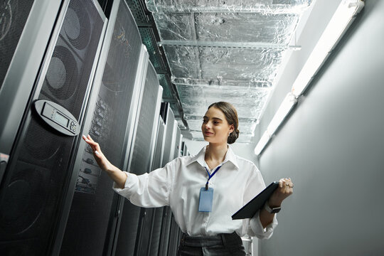 A woman in a white shirt manages server hardware in a contemporary data center setting.