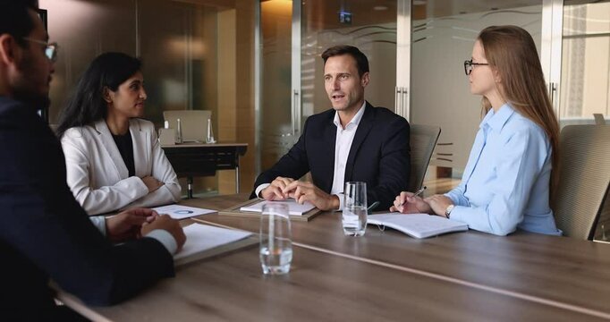 Handsome Hispanic businessman lead professional business meeting event seated at conference table with stakeholder or staff, express point, explain project details, provide information or consultation