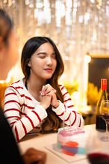 Asian people friends having celebration birthday party together at home with food and drink. Woman excited with birthday cake make a wish and blowing birthday candle with happiness.