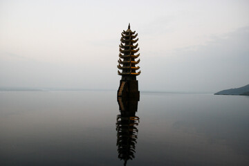 Tranquil scene of a miniature pagoda in a serene pond with calm waters, set against the backdrop of the East Vietnam Sea. A harmonious blend of nature and architecture.