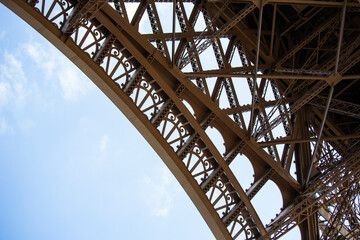 Naklejka premium Eiffel Tower steel leg detail with curving metallic structures and triangular shapes.