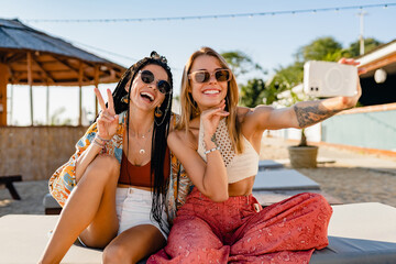 two stylish beautiful women relaxing having fun on beach in summer fashion trend outfit