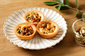 Caramel nut on the aesthetic plate. Walnut tart Shortbread tarts filled with caramel custard, pecans, and mixed nuts. Moist and tart dough. Nuts on top and dressed with caramel sauce.