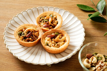 Caramel nut on the aesthetic plate. Walnut tart Shortbread tarts filled with caramel custard, pecans, and mixed nuts. Moist and tart dough. Nuts on top and dressed with caramel sauce.