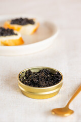 Black caviar in the gold jar with spoon and toasts on the table. Sturgeon caviar. Vertical orientation.