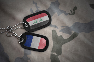 vintage army blank, dog tag with flag of iraq and france on the khaki texture background. military...