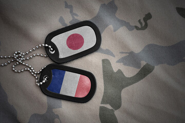 vintage army blank, dog tag with flag of japan and france on the khaki texture background. military...