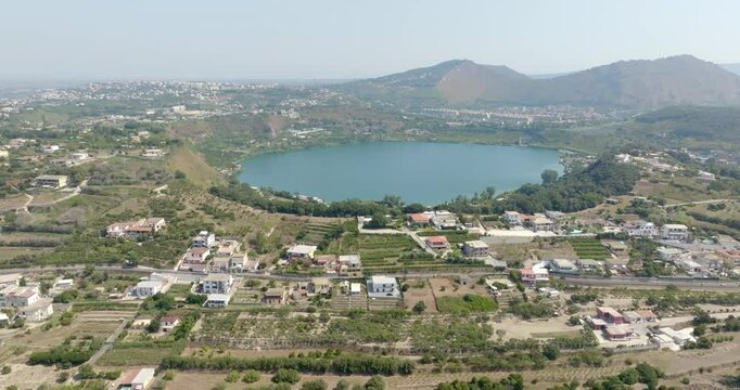 Aerial view of Lake Avernus (Lago d'Averno) located Pozzuoli, near Naples, in Campania, Italy. It is a volcanic crater lake located in Phlegraean Fields (Campi Flegrei). The lake is roughly circular.