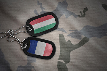 vintage army blank, dog tag with flag of hungary and france on the khaki texture background....