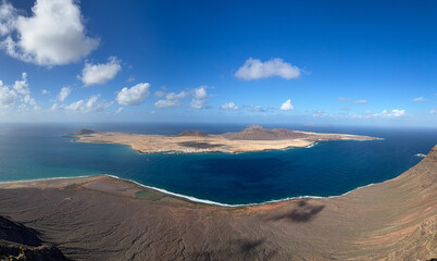 Breathtaking view from above from Mirador del Rio view point of Atlantic ocean, volcanic landscape and La Graciosa island on sunny day
