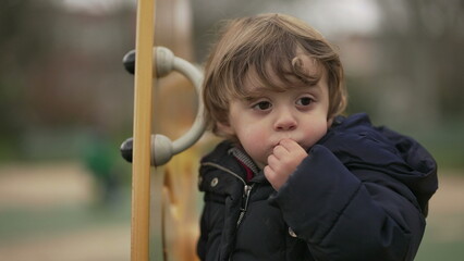 Obraz premium Contemplative little baby toddler boy portrait face at park thinking, lost in thought