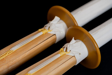 Two shinai for practice and competition in kendo. Japanese bamboo training sword imitating katana sword, used in kendo and other oriental martial arts, close-up on dark background, high resolution.