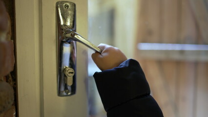 Little baby toddler opening front door and leaving home. Child leaves home reaching door knob