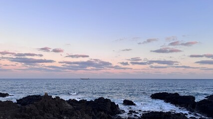 Obraz premium Sunset Over Calm Sea with Basalt Rocks and Soft Purple-Pink Tones