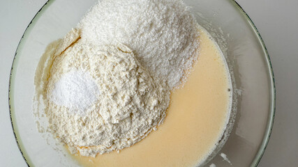 A close-up of flour, sugar, and yeast in a mixing bowl, highlighting baking preparation for holiday pastries