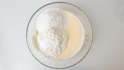 A glass bowl of flour and milk batter, symbolizing home baking, preparation for holiday treats, and culinary creativity