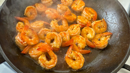 Juicy shrimp sizzling in a skillet, perfect for culinary arts, seafood recipes, or a coastal holiday feast