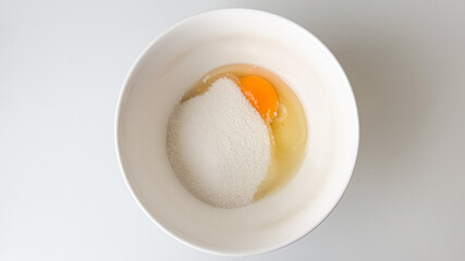 A bowl with raw egg and sugar, symbolizing baking preparation for Easter desserts