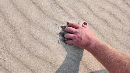 A hand gripping sandy beach represents relaxation and summer vacations, conveying the carefree essence of seaside holidays