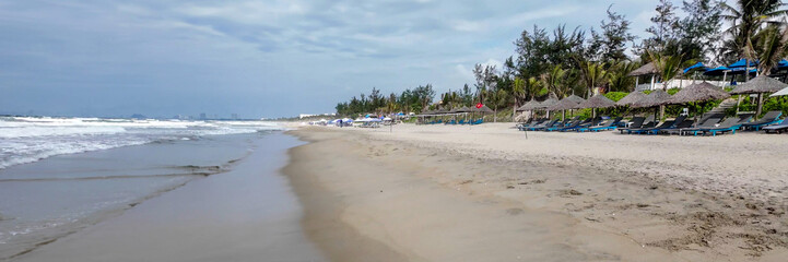 Empty tropical beach with lounge chairs and straw umbrellas, ideal for summer vacations and relaxation, emphasizing solitude and tranquility