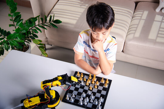 Asian little boy thinking and wait robot arm playing chess, STEM education E-learning, Funny children learning successful getting a lesson control robot arm game, Technology science education concept