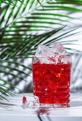 Sin cyn alcoholic cocktail drink with scotch whiskey, vermouth and liqueur. White marble table with palm leaves and shadows