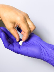 Fototapeta premium A person is holding a pill in their hand while wearing a purple glove