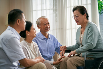 senior asian woman telling group of friends her story of misfortune