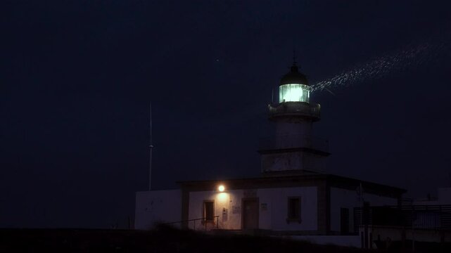 Faro iluminando mientras llueve a c&aacute;mara lenta