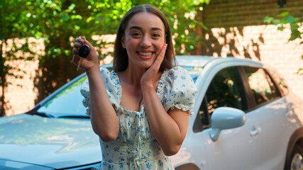Happy euphoric smiling Caucasian woman female car owner driver girl auto buyer rental service client looking at camera showing automobile keys gesturing excited holding key buy vehicle at town street