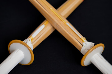 Two crossed shinai for practice and competition in kendo. Japanese bamboo training sword imitating katana sword, used in kendo and other oriental martial arts, close-up on dark background.