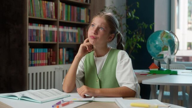 Pensive thoughtful Caucasian little girl puzzled child school kid student thinking solution pupil schoolgirl raising arm index finger pointing idea thought learning studying education indoor library