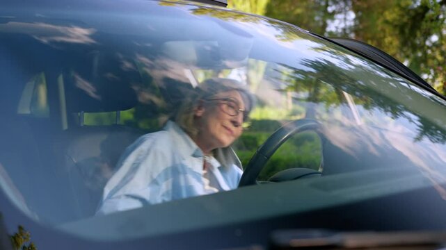 Glad aged Caucasian elderly woman female senior lady businesswoman pensioner car auto driver sitting inside new automobile rental vehicle rent motorcar fasten seat belt safety looking at camera smile