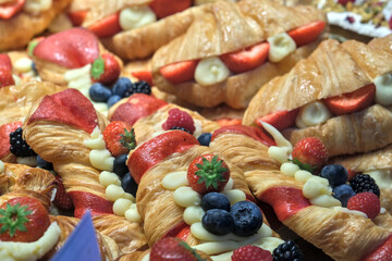 Freshly baked croissants filled with cream, strawberries, blueberries, and raspberries, creating a colorful and delicious display of pastries.