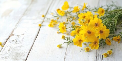 Obraz premium Vibrant yellow wildflowers scattered across a rustic white wooden table bathed in soft natural daylight creating a fresh serene atmosphere